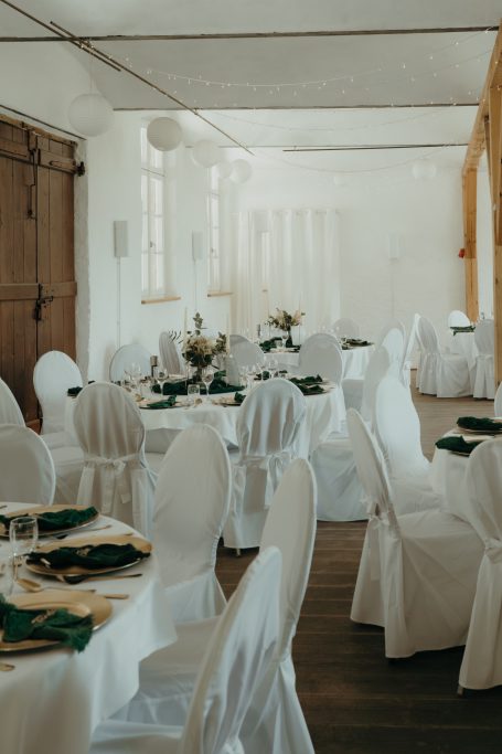 Elegante Tafel mit weißen Stühlen und grünem Tischdecken in einem hellen Raum.